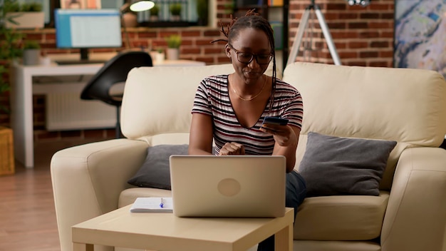 Young woman using credit card to shop online on website, buying clothes from retail store. Shopaholic adult making money payment and electronic transaction, doing purchase on sale.