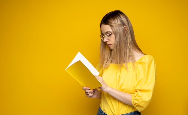 Young woman using digital tablet against yellow background