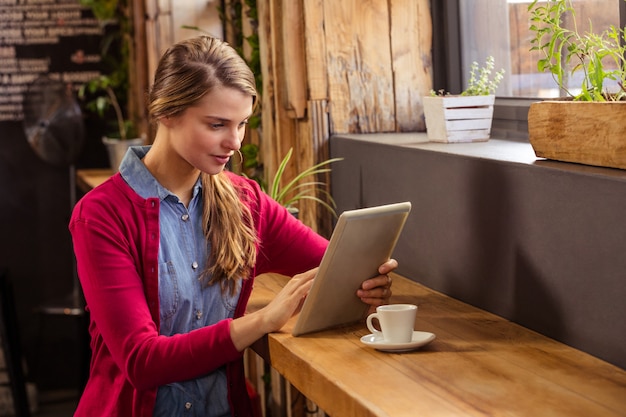 Young woman using digital tablet in cafeteria