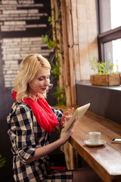 Young woman using digital tablet in cafeteria