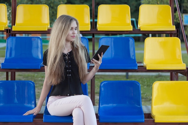 Foto giovane donna che usa un tablet digitale seduta su una sedia