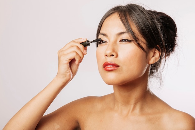 Young woman using eyeliner