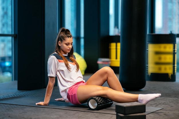 Young woman using a foam roller while doing stretching exercises