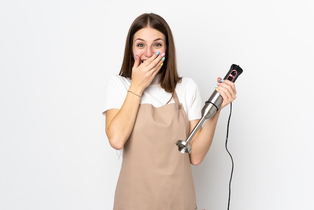 Young woman using hand blender on white with surprise facial expression