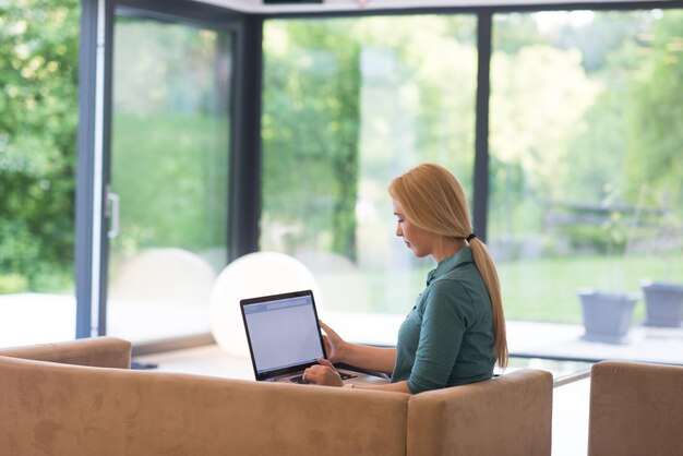 Young woman using her laptop computer in her luxury modern home, smiling