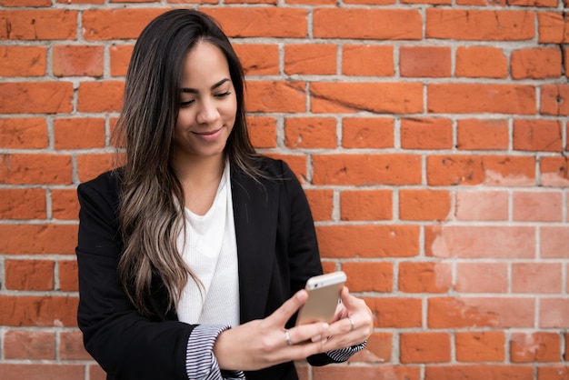 Giovane donna che per mezzo del suo telefono cellulare