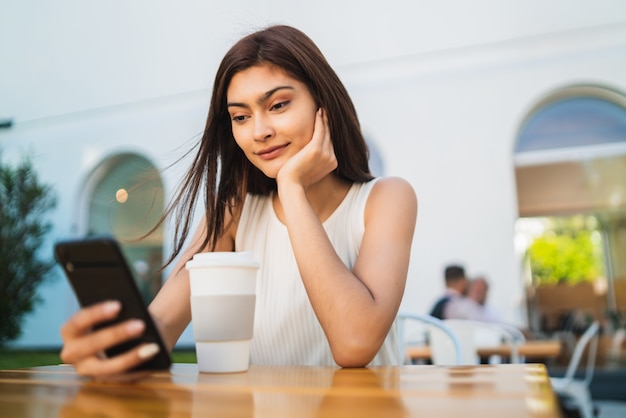 コーヒーショップで彼女の電話を使用して若い女性