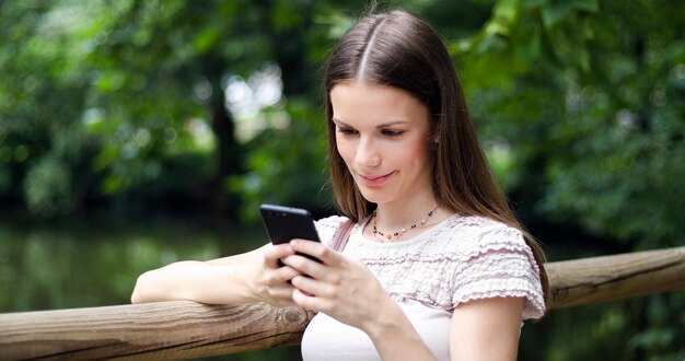 公園で彼女のスマートフォンを使用して若い女性