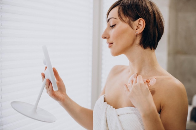 Young woman using jade face roller at home