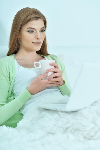 Young woman using laptop in bed at home