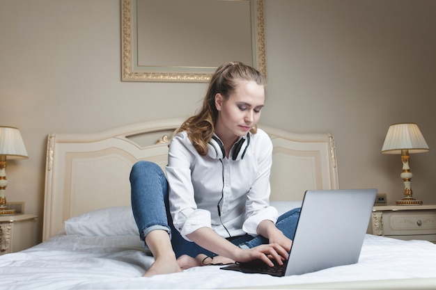 Young woman using laptop on the bed