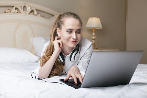 젊은 여자는 침대에서 노트북을 사용 하여