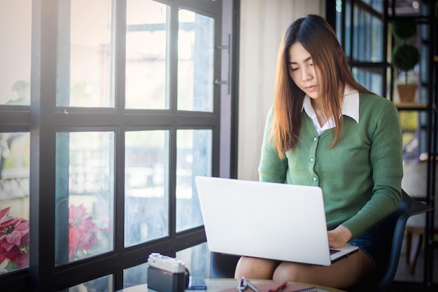 Young woman using laptop on chair