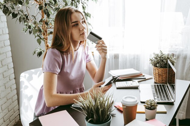 Photo young woman using laptop computer with credit card in office