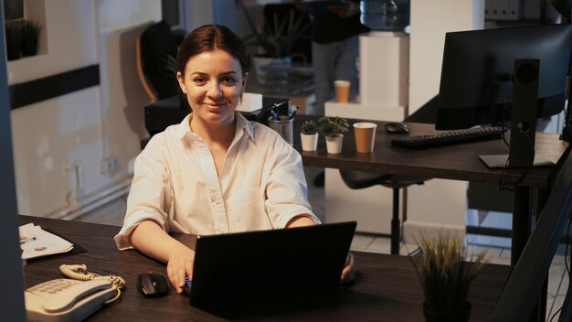 Photo young woman using laptop at desk in office