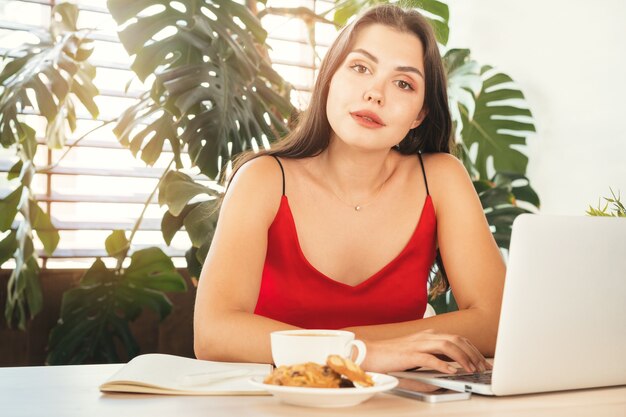 Young woman using laptop at home or in cafe