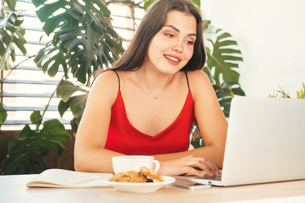 Giovane donna che utilizza computer portatile a casa o nel caffè