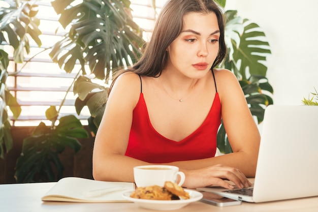Молодая женщина, используя ноутбук дома или в кафе