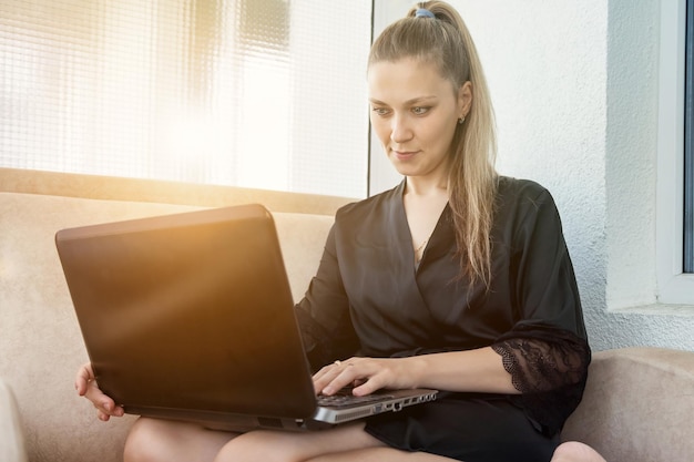 Giovane donna che usa il laptop a casa lavoro a distanza shopping online o istruzione chat sui social media