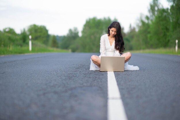 Photo young woman using laptop on rural road