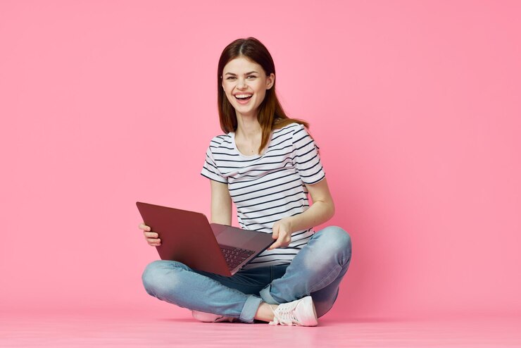 Photo young woman using laptop while sitting against yellow background