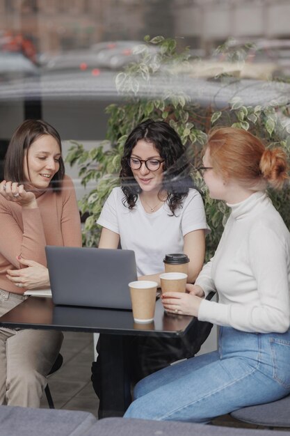 Photo young woman using laptop while sitting on chair at cafe