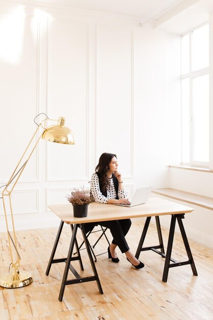 Photo young woman using laptop while sitting on chair at home