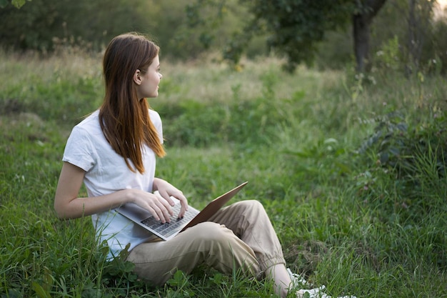 Young woman using laptop while sitting on field