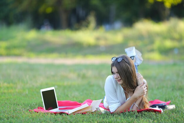 Young woman using laptop while sitting on field