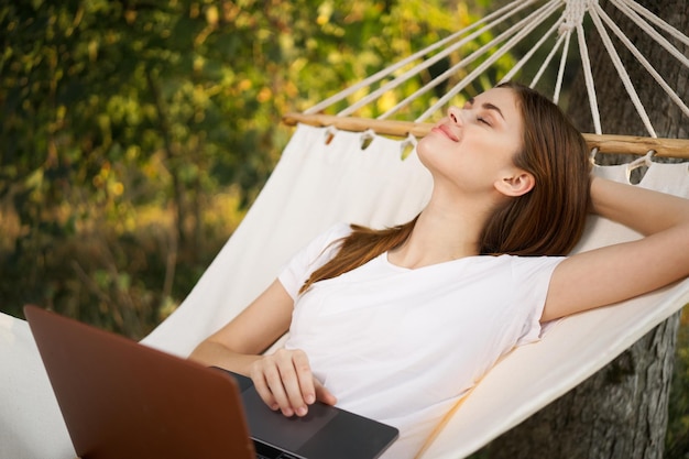 Photo young woman using laptop while sitting on hammock