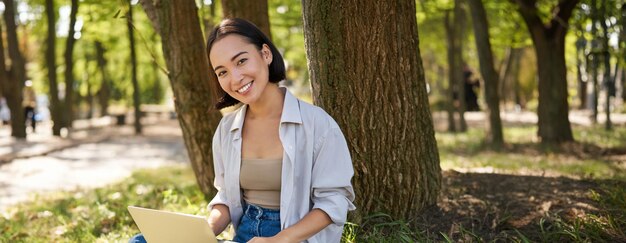 Young woman using laptop while sitting in park