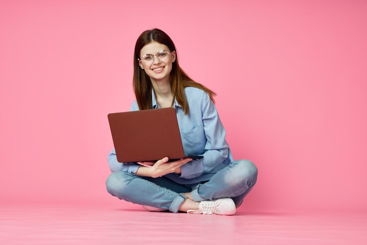Photo young woman using laptop while sitting on sofa against yellow background