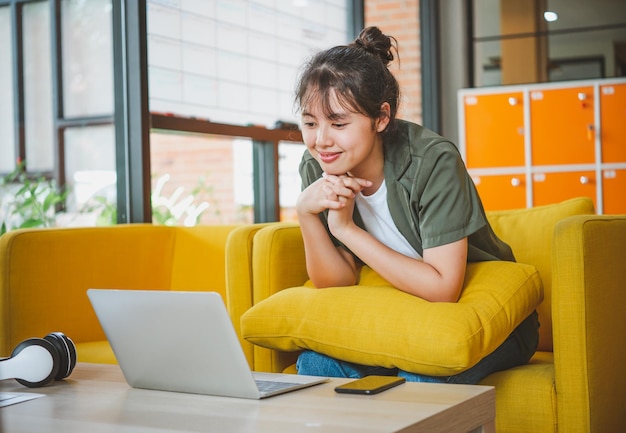 Young woman using laptop while sitting on sofa at home