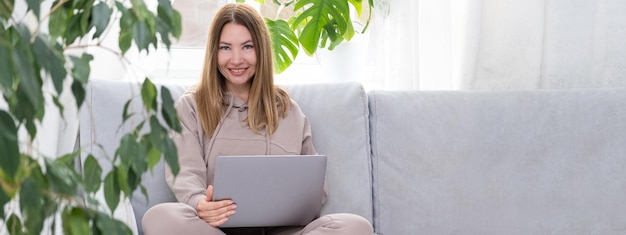 Photo young woman using laptop while sitting on sofa at home