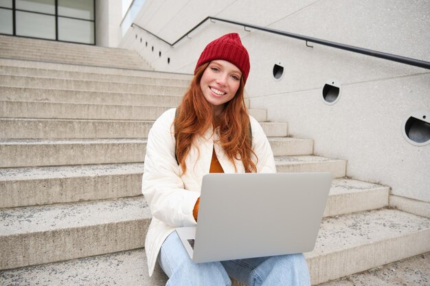 Photo young woman using laptop while sitting on steps