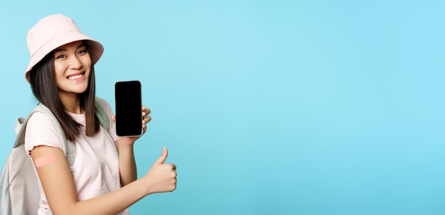 Young woman using mobile phone against blue background