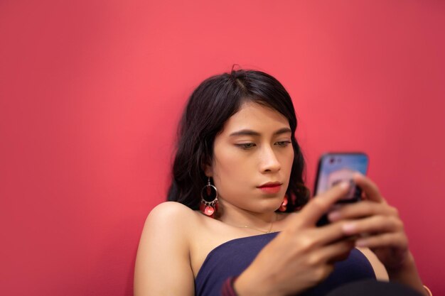 Young woman using mobile phone against red background