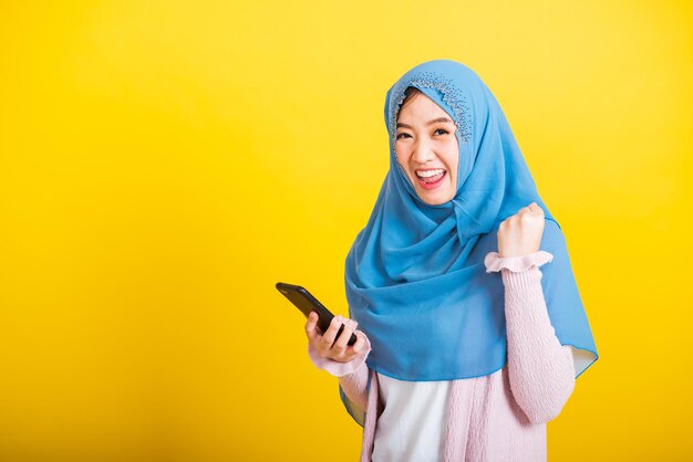 Young woman using mobile phone against yellow background