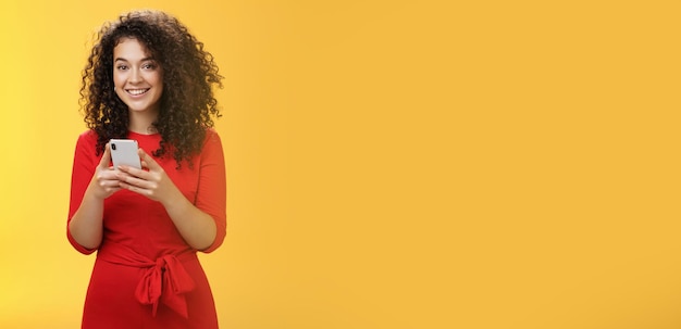 Photo young woman using mobile phone against yellow background