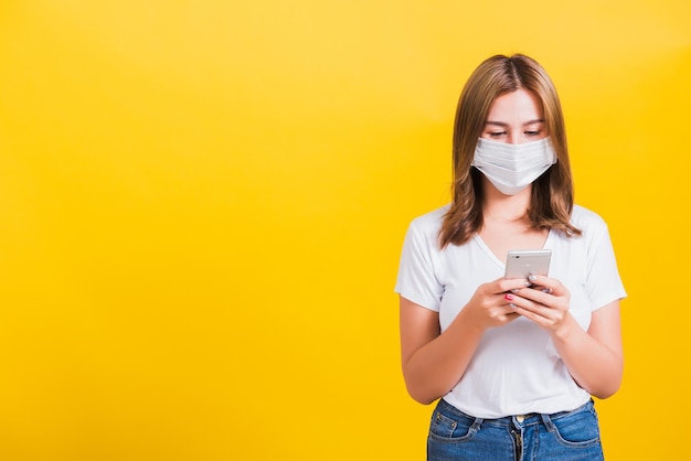 Young woman using mobile phone against yellow background