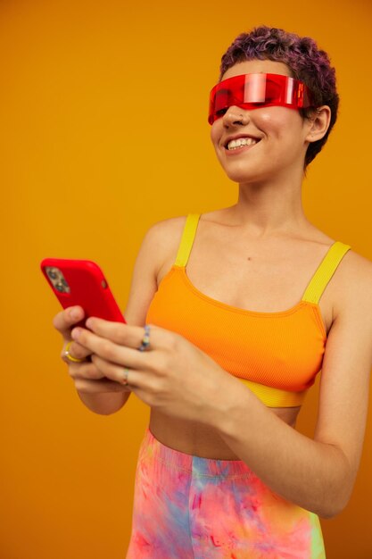 Young woman using mobile phone against yellow background