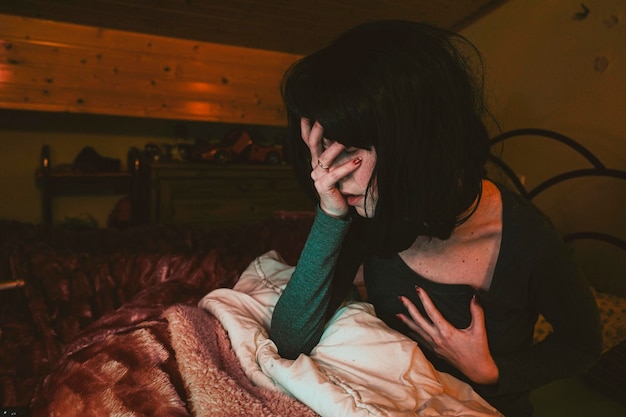 家のベッドで携帯電話を使っている若い女性