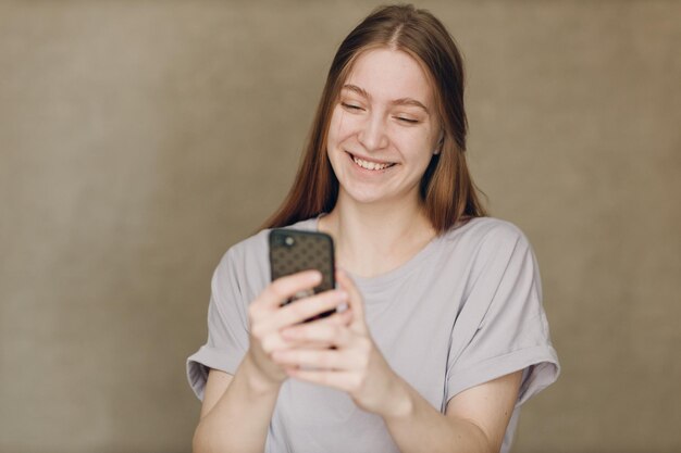 茶色の背景で携帯電話を使用して若い女性