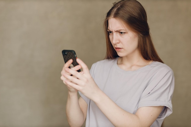 Young woman using mobile phone at brown background