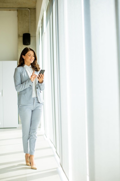 オフィスの窓際で携帯電話を使う若い女性