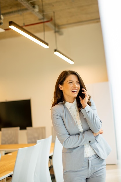 Young woman using mobile phone by the office window