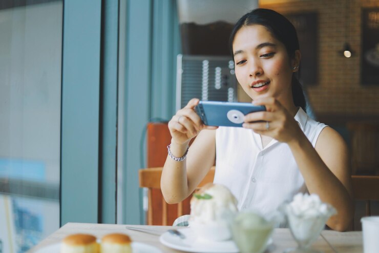 Photo カフェで携帯電話を使っている若い女性