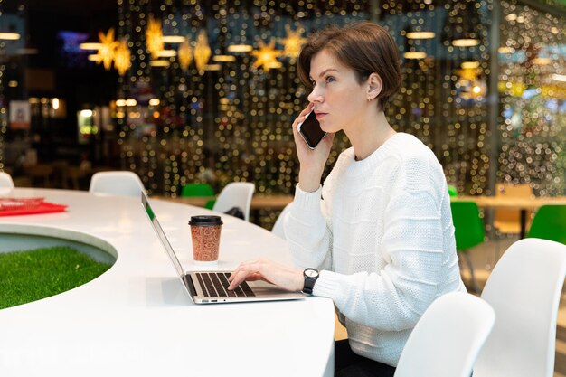 Foto giovane donna che usa il cellulare in un caffè