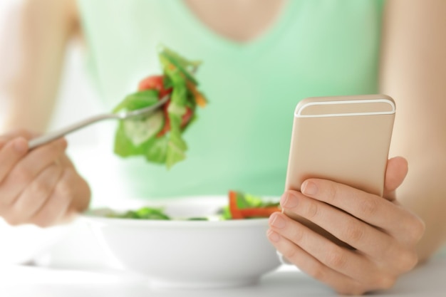 Photo young woman using mobile phone for counting calories while eating salad closeup weight loss concept