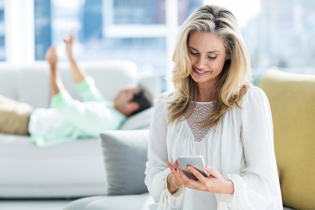 Giovane donna che per mezzo del telefono cellulare a casa